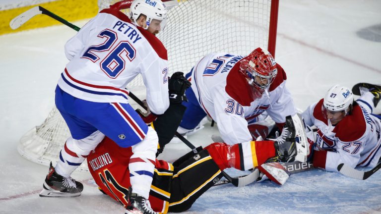 Montreal Canadiens' Jeff Petry, left, takes down Calgary Flames' Mikael Backlund as goalie Cayden Primeau, centre, and Alexander Romanov look on during third period NHL hockey action in Calgary, Saturday, April 24, 2021.(Jeff McIntosh/CP)
