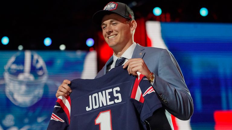 Alabama quarterback Mac Jones holds a team jersey after he was by the New England Patriots during the first round of the NFL draft, Thursday April 29, 2021, in Cleveland. (Tony Dejak/AP)