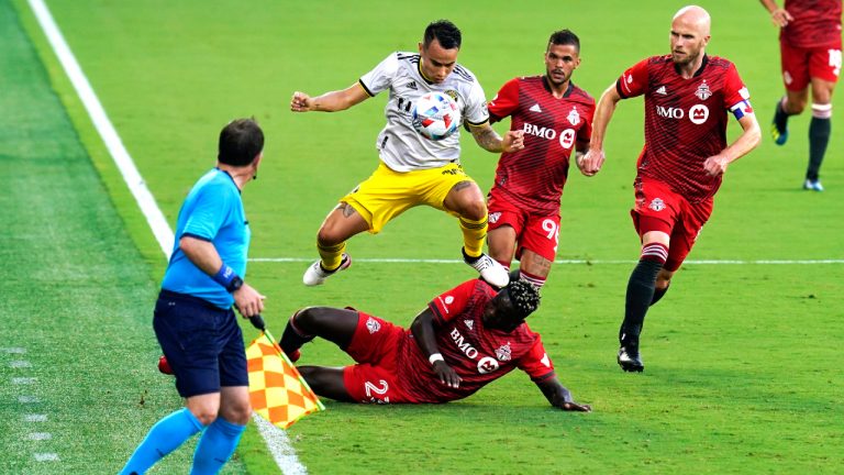 Columbus Crew midfielder Alexandru Matan, centre, moves the ball as he goes over Toronto FC defender Chris Mavinga (23) and past midfielder Michael Bradley, right, and defender Auro, second from right, during the first half of an MLS soccer match, Wednesday, May 12, 2021, in Orlando, Fla. (John Raoux/AP)