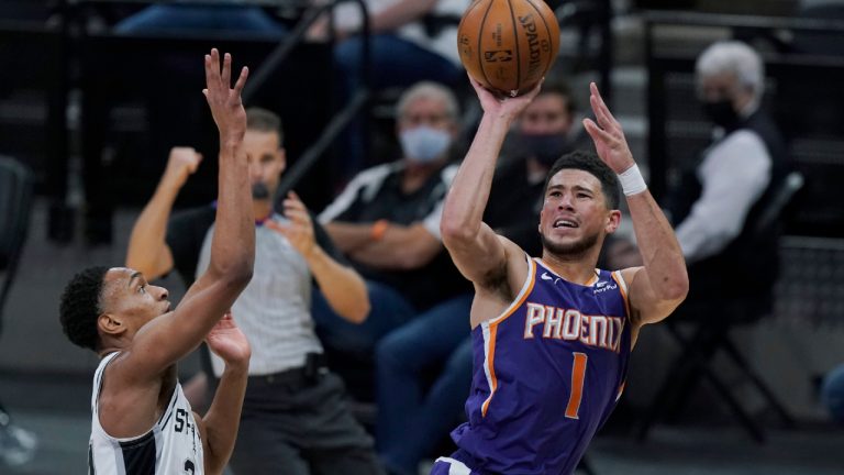 Phoenix Suns guard Devin Booker (1) shoots past San Antonio Spurs guard Devin Vassell (24) during the first half of an NBA basketball game in San Antonio, Saturday, May 15, 2021. (AP Photo/Eric Gay)