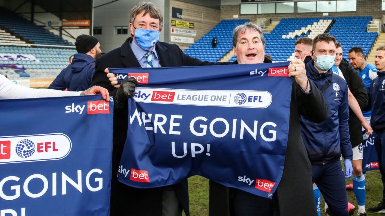 Canadian co-owners Jason Neale (left in mask) and R. Stewart Thompson celebrate after Peterborough United FC won promotion to England’s second-tier Championship with a 3-3 draw with Lincoln City in a May 1, 2021. (THE CANADIAN PRESS/HO-Peterborough United FC-Joe Dent)