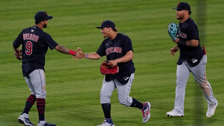 Cleveland Indians left fielder Eddie Rosario (9) shakes hands with right fielder Josh Naylor (22) after their baseball game against the Los Angeles Angels Tuesday, May 18, 2021, in Anaheim, Calif. Center fielder Harold Ramirez is at right. The Indians won 6-5. (Ashley Landis/AP)