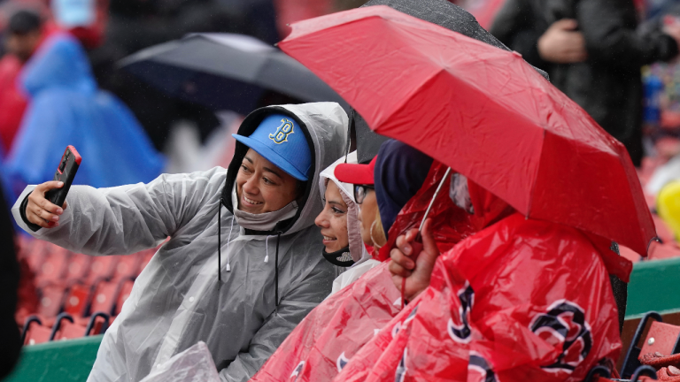 Jazmin Lopez, left, takes a selfie that includes her wife, Glenda Lopez, second from left, both of Fitchburg, Mass., while waiting for the start of a baseball game between the Miami Marlins and the Boston Red Sox, Sunday, May 30, 2021, in Boston. Sunday's game was postponed due to weather. (Steven Senne / AP) 