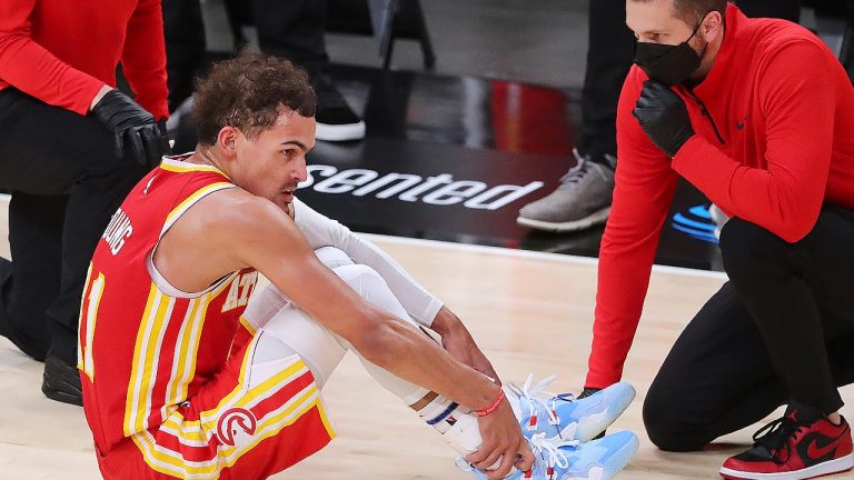 Atlanta Hawks guard Trae Young grabs his ankle after falling to the floor against the Milwaukee Bucks during the third quarter in Game 3 of the NBA Eastern Conference basketball finals, Sunday, June 27, 2021, in Atlanta. (Curtis Compton/Atlanta Journal-Constitution via AP)