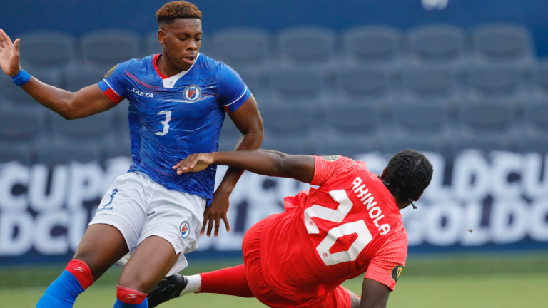 Canada forward Ayo Akinola (20) is knocked to the ground by Haiti defender Francois Dulysse (3) during the second half of a CONCACAF Gold Cup soccer match in Kansas City, Kan., Thursday, July 15, 2021. Dulysse was issued a red card. (Colin E. Braley / AP)