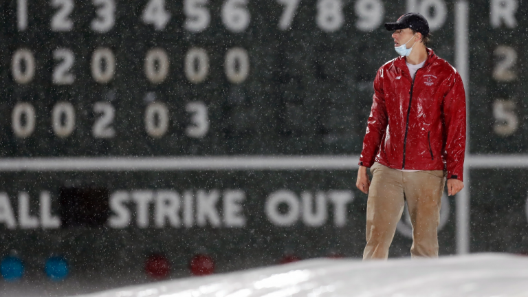 A member of the Fenway Park grounds crew works to cover the infield with the tarp during a rain delay during a baseball game between the Boston Red Sox and the Miami Marlins during the sixth inning Friday, May 28, 2021, in Boston. (Michael Dwyer / AP) 