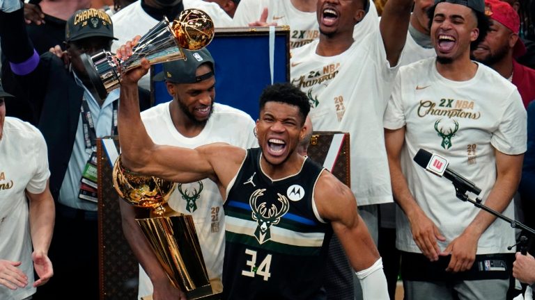 Milwaukee Bucks forward Giannis Antetokounmpo (34) reads with the championship trophy after defeating the Phoenix Suns in Game 6 of basketball's NBA Finals in Milwaukee, Tuesday, July 20, 2021. The Bucks won 105-98. (Paul Sancya/AP)