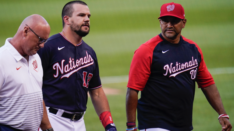 Washington Nationals' Kyle Schwarber, center, hobbles off the field next to trainer Paul Lessard, left, and manager Dave Martinez during the second inning of a baseball game against the Los Angeles Dodgers, Friday, July 2, 2021, in Washington. (Julio Cortez / AP) 