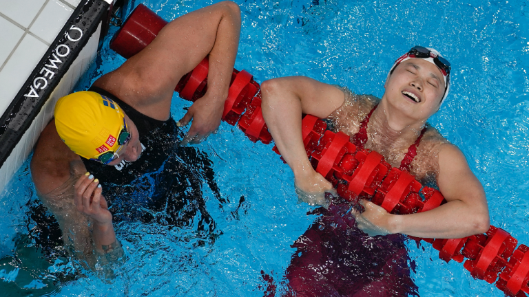Margaret MacNeil, right, of Canada, reacts after winning the final of the women's 100-meter butterfly as Sarah Sjoestroem, of Sweden, looks on at the 2020 Summer Olympics, Monday, July 26, 2021, in Tokyo, Japan. (David J. Phillip / AP)
