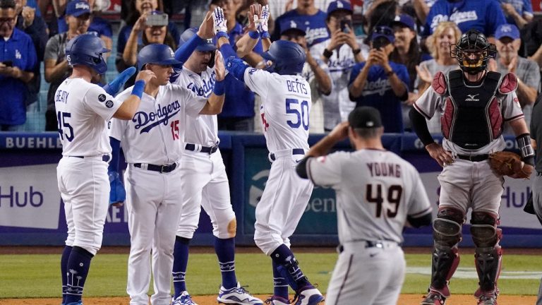 Los Angeles Dodgers' Mookie Betts, third from right, is congratulated by Matt Beaty, left, Austin Barnes, second from left, and AJ Pollock, third from left, after hitting a grand slam as Arizona Diamondbacks starting pitcher Alex Young, second from right, watches along with catcher Bryan Holaday during the seventh inning of a baseball game Saturday, July 10, 2021, in Los Angeles. (Mark J. Terrill/AP)