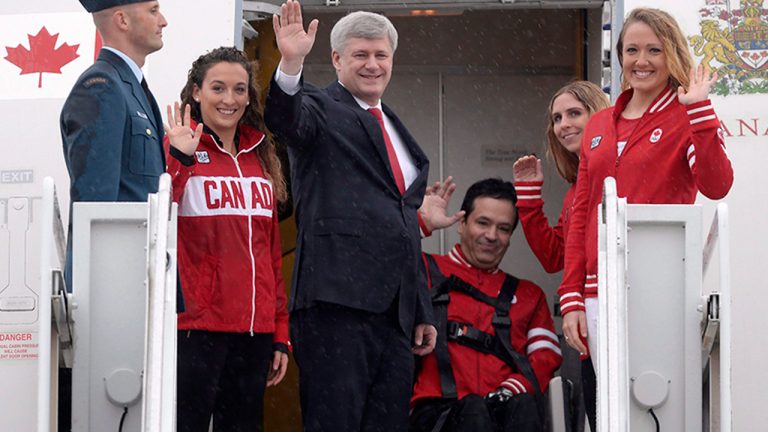 Prime Minister Stephen Harper, centre, accompanied by Canadian Pan Am and Parapan Am athletes Elise Marcotte, second left, Marco Dispaltro, third from right, Priscilla Gagne, second from right, and Tera Van Beilen, right, waves as he departs for Panama to participate in the Summit of the Americas, in Ottawa on Friday, April 10, 2015. (Adrian Wyld/CP)