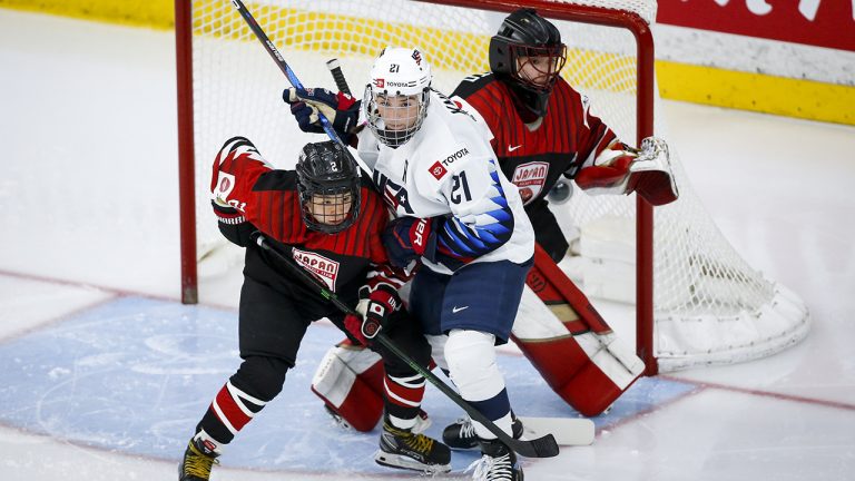 Hilary Knight, centre, of the United States, tries to hold her position as Japan's Shiori Koike checks in front of goalie Nana Fujimoto during second period quarterfinal IIHF Women's World Championship hockey action in Calgary, Alta., Saturday, Aug. 28, 2021. (Jeff McIntosh/CP)