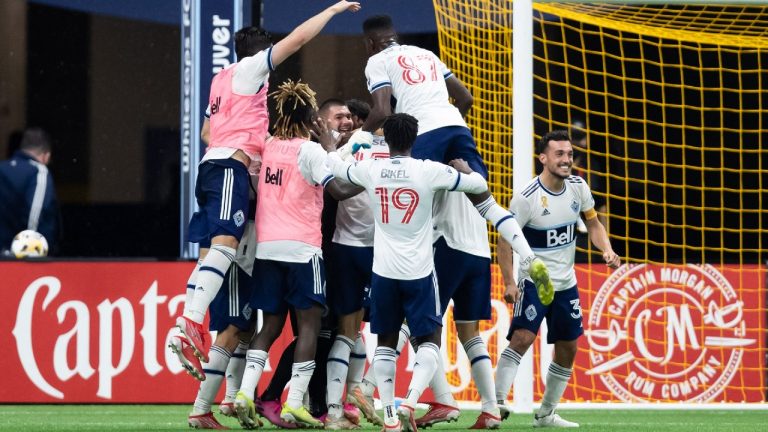 Vancouver Whitecaps goalkeeper Maxime Crepeau, back centre, is mobbed by his teammates after Vancouver defeated FC Dallas during an MLS soccer game in Vancouver, on Saturday, September 25, 2021. (Darryl Dyck/CP)