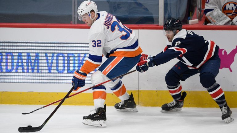 New York Islanders left wing Ross Johnston (32) skates with the puck next to Washington Capitals defenseman Justin Schultz (2) during the first period of an NHL hockey game Tuesday, Jan. 26, 2021, in Washington (Nick Wass/AP).