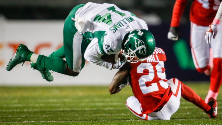 Saskatchewan Roughriders' D'haquille Williams, left, is tackled by Calgary Stampeders' Jamar Wall during first half CFL football action in Calgary, Saturday, Oct. 23, 2021. (Jeff McIntosh/The Canadian Press)