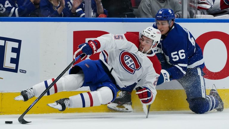 Montreal Canadiens forward Ryan Poehling (25) gets taken out by Toronto Maple Leafs defenceman Kristians Rubins (56) during second period NHL pre-season hockey action in Toronto on Tuesday, October 5, 2021. (Nathan Denette/The Canadian Press)