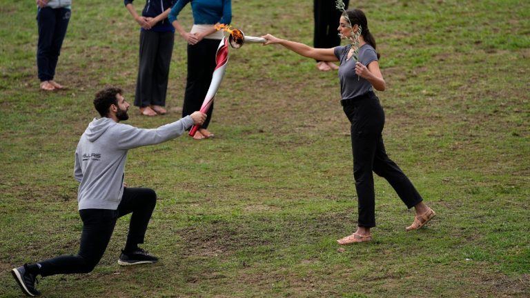 Greek actress Xanthi Georgiou, playing the role of the High Priestess, passes the flame to a torch bearer during the final rehearsal for the lighting of the Olympic flame at Ancient Olympia site, birthplace of the ancient Olympics in southwestern Greece, Sunday, Oct. 17, 2021. The flame will be transported by torch relay to Beijing, China, which will host the Feb. 4-20, 2022 Winter Olympics. (Thanassis Stavrakis/AP)