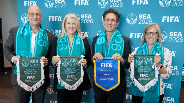 From left, Kasey Keller, former goalkeeper for the MLS soccer Seattle Sounders and the U.S. Men's National Team; Beth Knox, president of the Seattle Sports Commission; Sounders owner Adrian Hanauer; and former U.S. Women's National Team goalkeeper Amy Griffin pose for a photo Monday, Nov. 1, 2021, in Seattle with scarves and banners representing Seattle's bid to become a host city for the FIFA World Cup in 2026. (AP) 