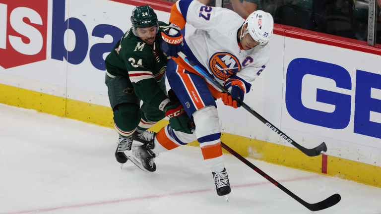 New York Islanders' Anders Lee (27) and Minnesota Wild's Matt Dumba (24) go after the puck during the third period of an NHL hockey game Sunday, Nov. 7, 2021, in St. Paul, Minn. (AP Photo/Stacy Bengs)