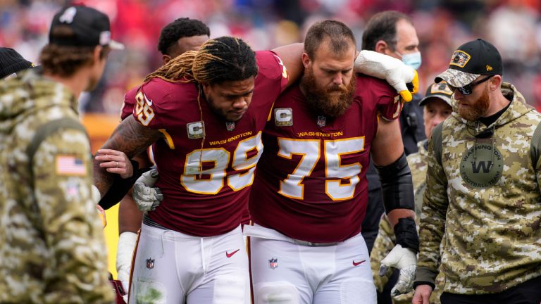 Washington Commanders defensive end Chase Young (99) is helped off the field by guard Brandon Scherff (75) after an injury during the first half of an NFL football game against the Tampa Bay Buccaneers. (Nick Wass/AP)
