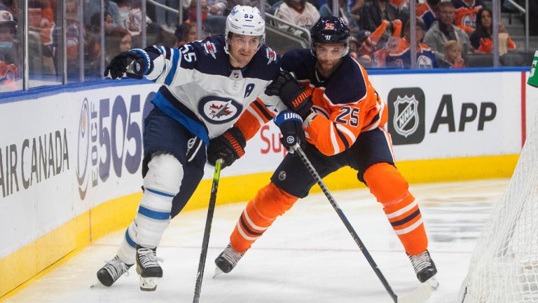Winnipeg Jets' Mark Scheifele (55) and Edmonton Oilers' Darnell Nurse (A) (25) battle for the puck during third period NHL preseason action in Edmonton on Saturday, October 2, 2021.(Jason Franson/CP)