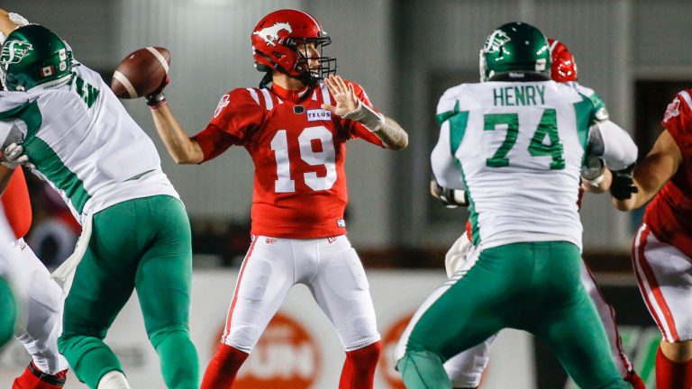 Calgary Stampeders quarterback Bo Levi Mitchell, centre, throws the ball while under pressure from the Saskatchewan Roughriders during first half CFL football action. (Jeff McIntosh/CP)