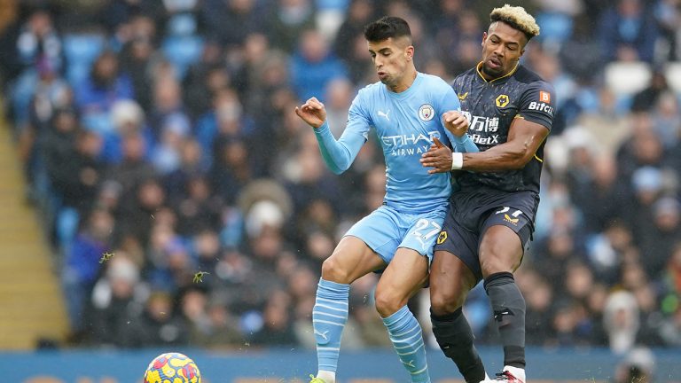 Manchester City's Joao Cancelo, left, challenges for the ball with Wolverhampton Wanderers' Adama Traore during the English Premier League soccer match between Manchester City and Wolverhampton Wanderers, at the Etihad stadium in Manchester, England, Saturday, Dec.11, 2021. (Dave Thompson/AP)