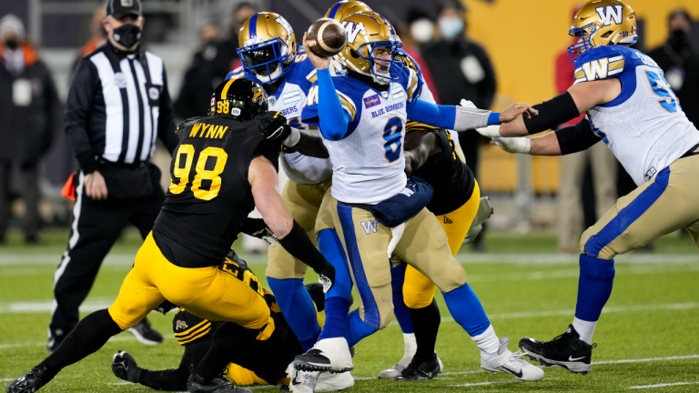 Winnipeg Blue Bombers quarterback Zach Collaros (8) throws the ball under pressure from Hamilton Tiger-Cats defensive tackle Dylan Wynn (98) during first half football action in the 108th CFL Grey Cup in Hamilton, Ont., on Sunday, December 12, 2021. THE CANADIAN PRESS/Ryan Remiorz