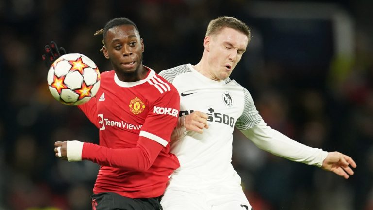 Manchester United's Aaron Wan-Bissaka, left, and Young Boys' Michel Aebischer battle the for the ball during the Champions League group F soccer match between Manchester United and Young Boys, at Old Trafford stadium in Manchester, England, Wednesday, Dec. 8, 2021. (Dave Thompson/AP Photo) 
