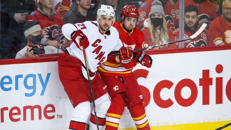 Carolina Hurricanes' Nino Niederreiter, left, checks Calgary Flames' Johnny Gaudreau during first period NHL hockey action in Calgary, Thursday, Dec. 9, 2021. (Jeff McIntosh/THE CANADIAN PRESS)
