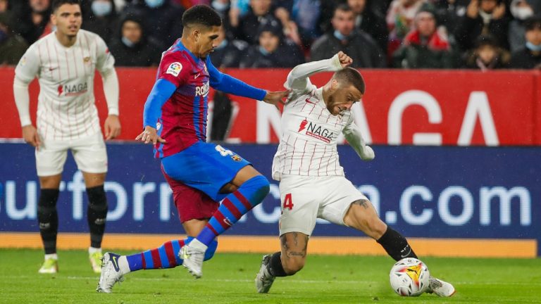 Sevilla's Papu Gomez, right, vies for the ball with Barcelona's Ronald Araujo during the Spanish La Liga soccer match between Sevilla and Barcelona at the Ramon Sanchez-Pizjuan stadium, in Seville, Spain, Tuesday, Dec. 21, 2021. (Angel Fernandez/AP) 
