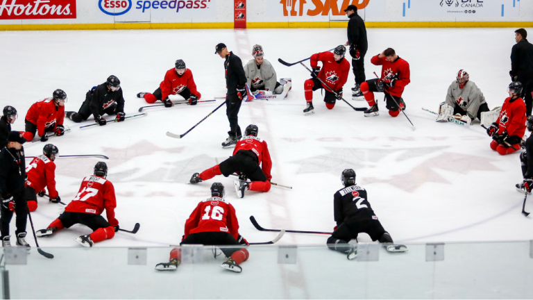 Players stretch as head coach Dave Cameron, centre left, gives instruction during a practice at the Canadian World Junior Hockey Championships selection camp in Calgary, Thursday, Dec. 9, 2021 (Jeff McIntosh/CP).