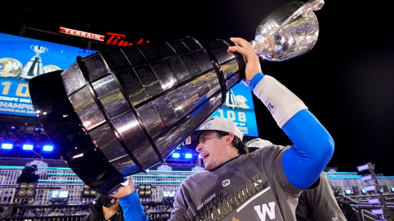 Winnipeg Blue Bombers quarterback Zach Collaros (8) hoists the trophy as he celebrates defeating the Hamilton Tiger-Cats in the 108th CFL Grey Cup in Hamilton, Ont., on Sunday, December 12, 2021 (Nathan Denette/CP).