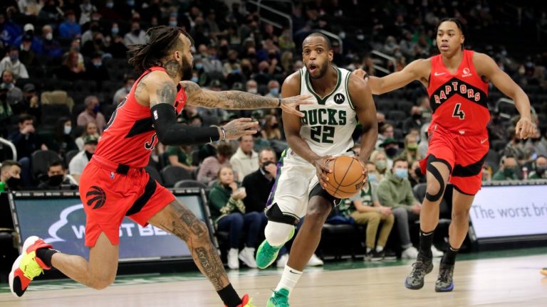 Milwaukee Bucks' Khris Middleton (22) drives to the basket between Toronto Raptors' Gary Trent Jr. and Scottie Barnes (4) during the second half of an NBA basketball game Wednesday, Jan. 5, 2022, in Milwaukee. (Aaron Gash/AP) 
