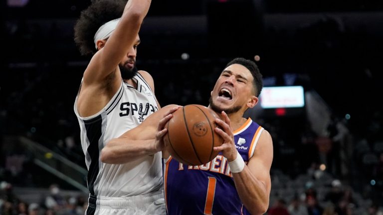 Phoenix Suns guard Devin Booker (1) is fouled as he drives to the basket against San Antonio Spurs guard Derrick White, left, during the second half of an NBA basketball game, Monday, Jan. 17, 2022, in San Antonio. (Eric Gay/AP) 