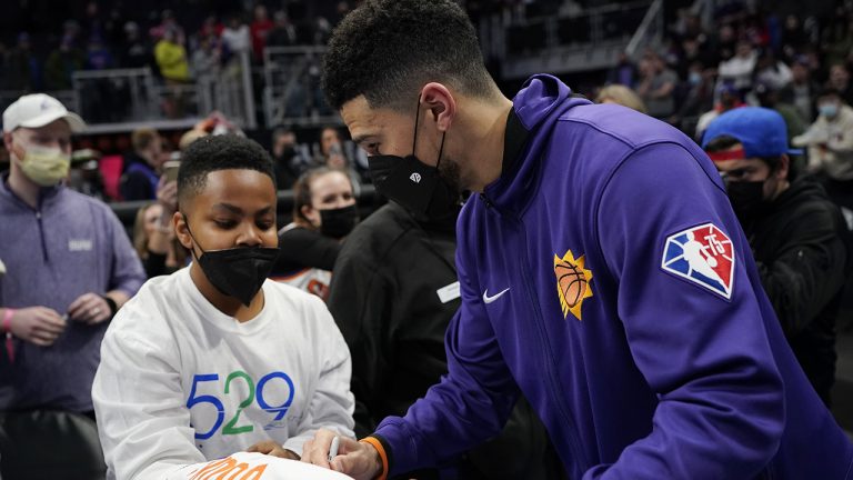 Phoenix Suns guard Devin Booker signs a jersey after the second half of an NBA basketball game against the Detroit Pistons. (Carlos Osorio/AP)