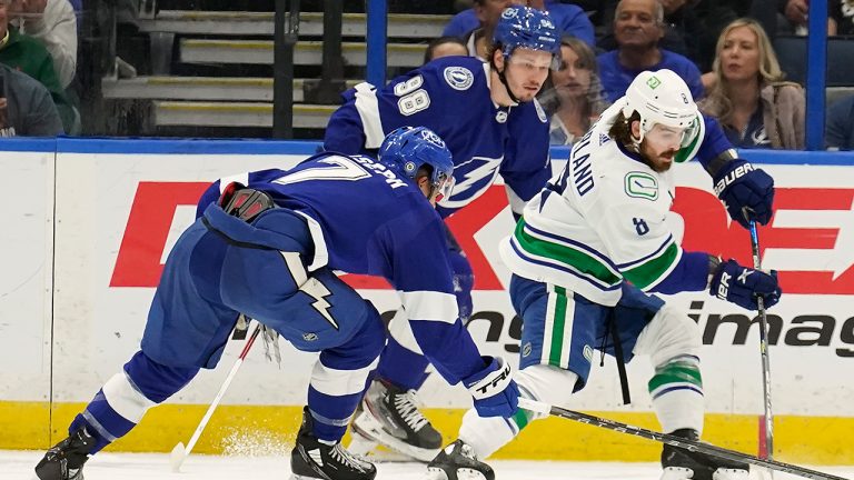 Vancouver Canucks right wing Conor Garland (8) is double teammated by Tampa Bay Lightning right wing Mathieu Joseph (7) and defenseman Mikhail Sergachev (98) during the second period of an NHL hockey game Thursday, Jan. 13, 2022, in Tampa, Fla. (Chris O'Meara/AP)