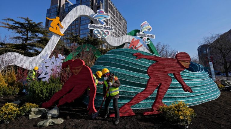 Workers wearing face masks to help protect from the coronavirus set up a decoration for the Winter Olympic Games in Beijing, Sunday, Jan. 16, 2022. Beijing has reported its first local omicron infection, according to state media, weeks before the Winter Olympic Games are due to start. (Andy Wong/AP)