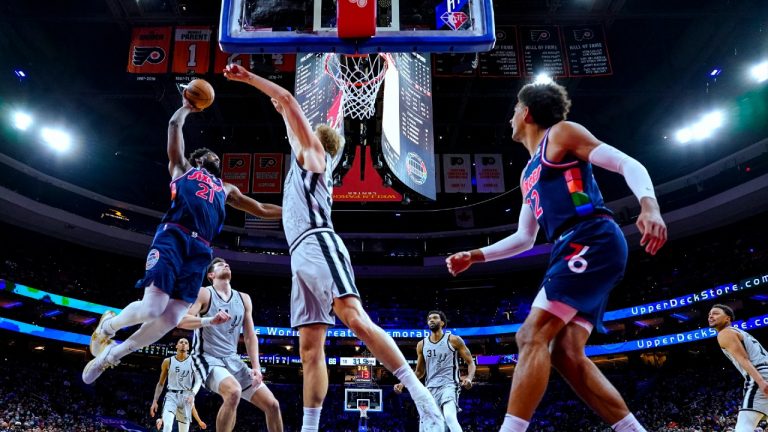 Philadelphia 76ers' Joel Embiid, left, goes up for a dunk against San Antonio Spurs' Keita Bates-Diop, center, during the first half of an NBA basketball game Friday, Jan. 7, 2022, in Philadelphia. (Chris Szagola/AP) 