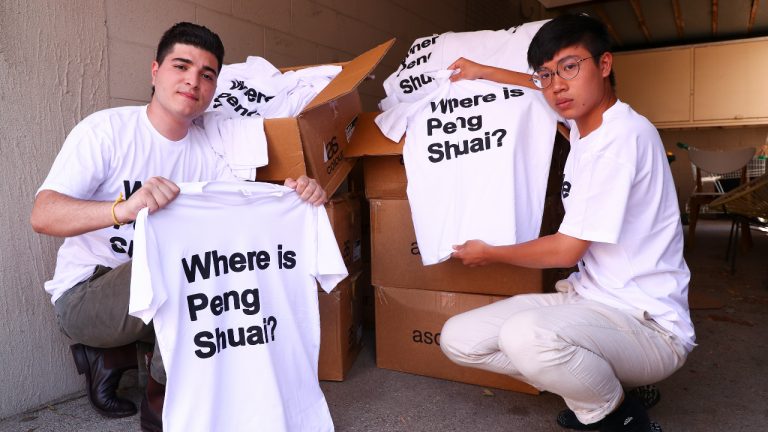 Drew Pavlou, left, and Max Mok show some of the 1,000 shirts they plan to hand out to patrons ahead of Saturday's women's singles final at the Australian Open tennis championships. (Tertius Pickard/AP) 