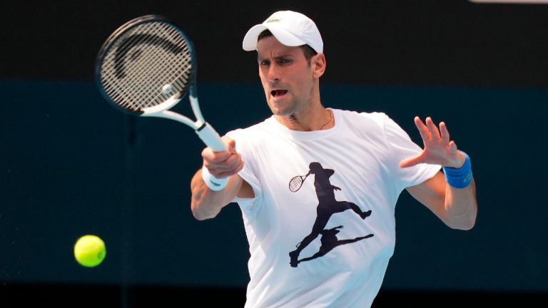In this photo supplied by Tennis Australia, defending champion Serbia's Novak Djokovic practices in the Rod Laver Arena ahead of the Australian Open at Melbourne Park in Melbourne, Australia, Tuesday, Jan. 11, 2022. (Scott Barbour/Tennis Australia via AP)