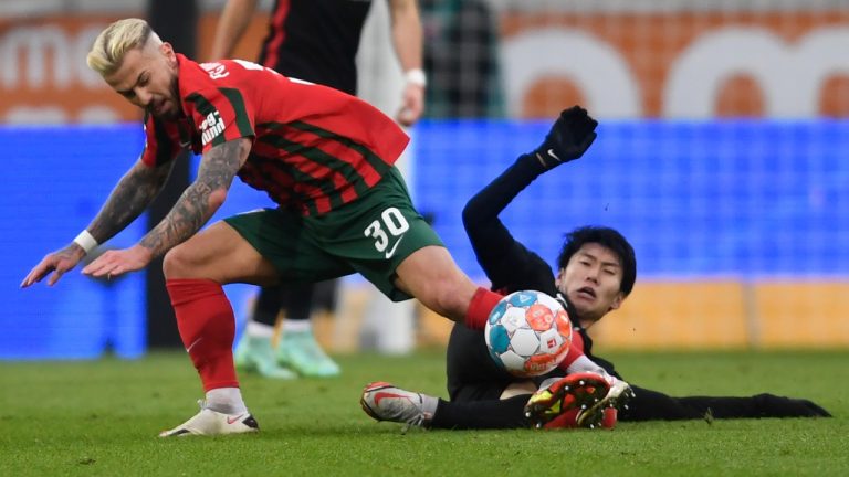 Frankfurt's Daichi Kamada, right, falls in an attempt to take control of the ball from Augsburg's Niklas Dorsch during the German Bundesliga soccer match between Eintracht Frankfurt and FC Augsburg at the WWK Arena in Augsburg, Germany, Sunday, Jan. 16, 2022. (Andreas Schaad/AP)