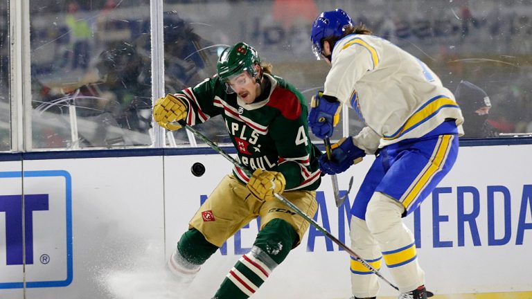 Minnesota Wild defenceman Jon Merrill (4) and St. Louis Blues center Oskar Sundqvist (70) compete for the puck during the first period of the NHL Winter Classic hockey game Saturday, Jan. 1, 2022, at Target Field in Minneapolis. (Andy Clayton-King/AP)