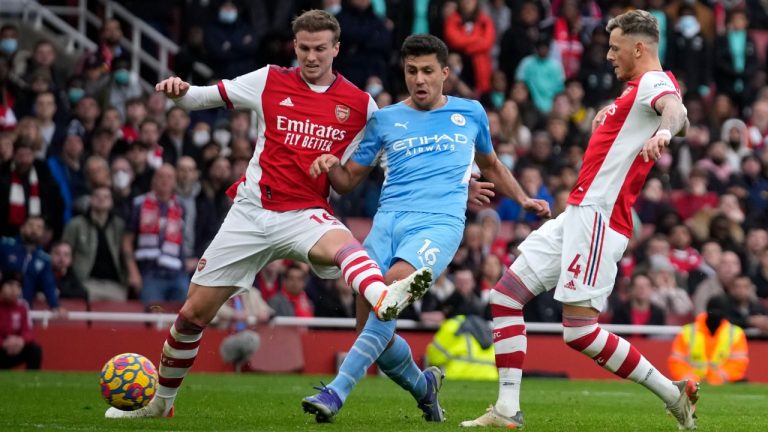 Manchester City's Rodrigo, center, shoots to score his sides second goal past Arsenal's Rob Holding, left, and Arsenal's Ben White during the Premier League soccer match between Arsenal and Manchester City at the Emirates Stadium, in London, England, Saturday Jan. 1, 2022. (Matt Dunham/AP)