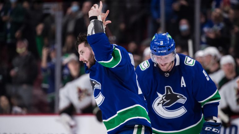 Vancouver Canucks' Kyle Burroughs, left, reacts to the crowd as he skates to the penalty box past J.T. Miller after fighting Arizona Coyotes' Lawson Crouse during the third period of an NHL hockey game in Vancouver, on Tuesday, February 8, 2022. (Darryl Dyck/CP)