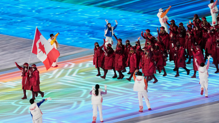 Charles Hamelin and Marie-Philip Poulin carry the Canadian flag as they enter the stadium along with members of Team Canada during the opening ceremony at the Beijing Winter Olympics in Beijing, China, on Friday, Feb. 4, 2022. (CP)