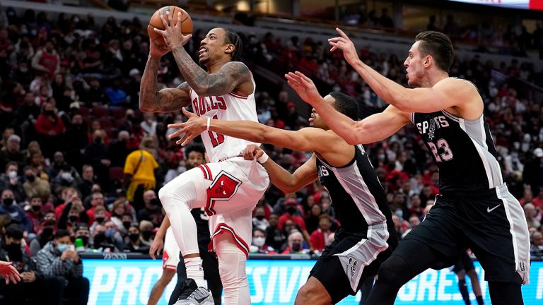 Chicago Bulls' DeMar DeRozan, left, drives past and scores on San Antonio Spurs' Keldon Johnson, center, and Zach Collins during the second half of an NBA basketball game Monday, Feb. 14, 2022, in Chicago. The Bulls won 120-109. (Charles Rex Arbogast/AP)