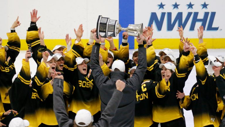 Boston Pride players cheer as coach Paul Mara hoists the NWHL Isobel Cup trophy after the team's win over the Minnesota Whitecaps in the championship hockey game in Boston, Saturday, March 27, 2021. With a new name and an influx of private ownership, the Premier Hockey Federation — formerly the National Women's Hockey League — prepares to open its seventh season this weekend, and first with a full slate of games in two years. (Mary Schwalm/AP)