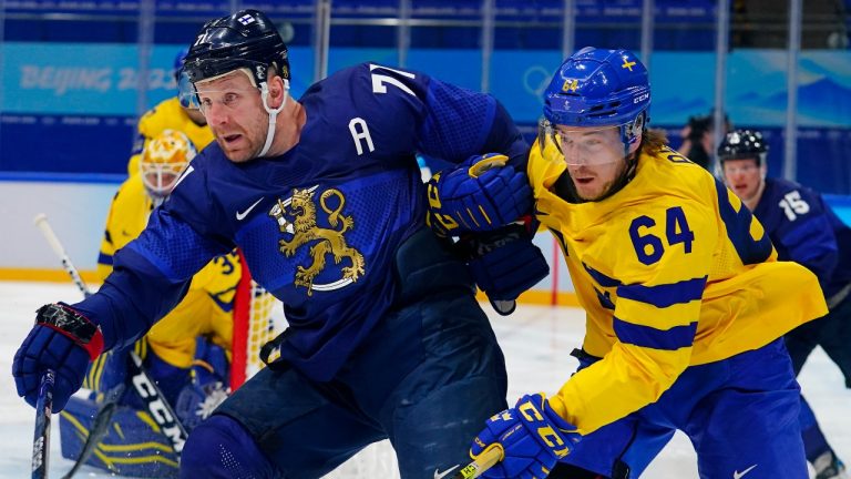 Finland's Leo Komarov (71) battles with Sweden's Jonathan Pudas (64) during a preliminary round men's hockey game at the 2022 Winter Olympics, Sunday, Feb. 13, 2022, in Beijing. (Matt Slocum/AP Photo)