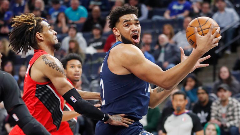 Minnesota Timberwolves center Karl-Anthony Towns, right, goes to the basket around Portland Trail Blazers forward Greg Brown III in the first quarter of an NBA basketball game Monday, March 7, 2022, in Minneapolis. (AP Photo/Bruce Kluckhohn)